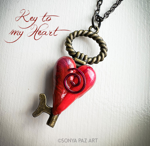 Red heart-shaped key pendant on a chain with a twisted bronze ring; caption 'Key to my Heart' visible.