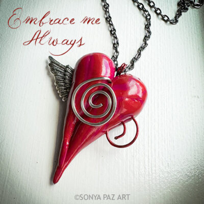 Red glass heart pendant with spiral metal accents and a small wing on a chain, with the cursive text 'Embrace me Always' above and a watermark reading '©SONYA PAZ ART' at the bottom.