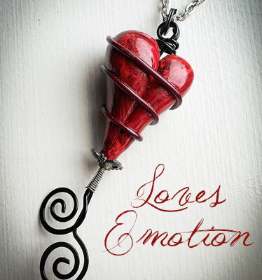 Red heart pendant wrapped in silver wire, hanging from a chain, with the text 'Loves Emotion' beside it.
