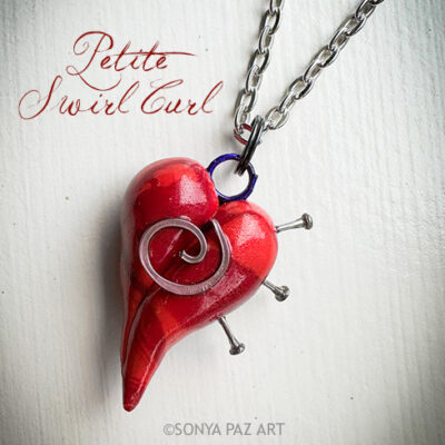 Red heart-shaped pendant pierced by nails on a silver chain, as part of an artistic jewelry piece with cursive 'Petite Swirl Curl' text.