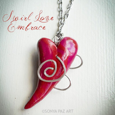 Pink horn-shaped pendant with silver spirals on a chain against a white background (art necklace).